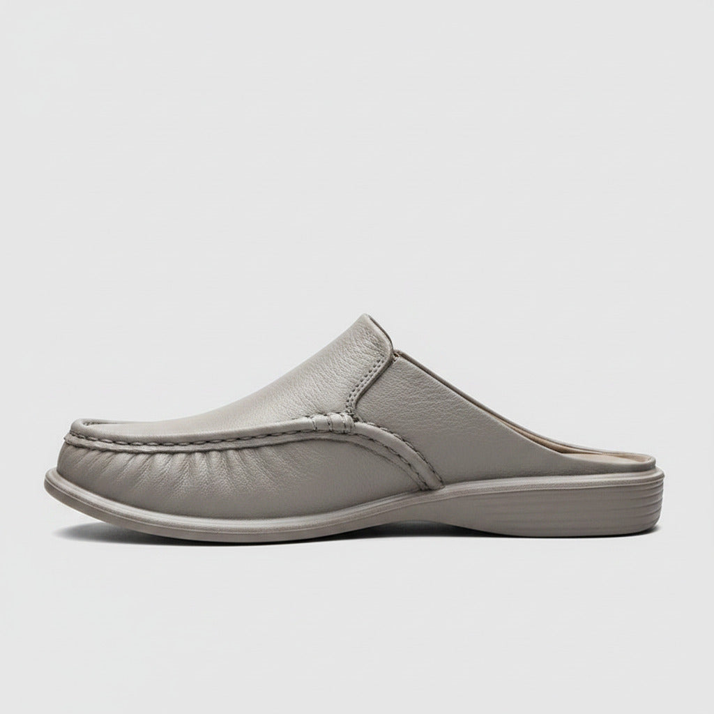 Gray slip-on shoe worn by a person sitting on a wooden bench.