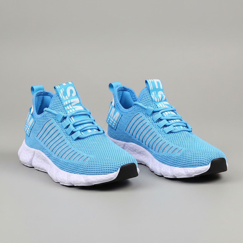 Blue athletic shoes with white soles worn by a person on a wooden floor.