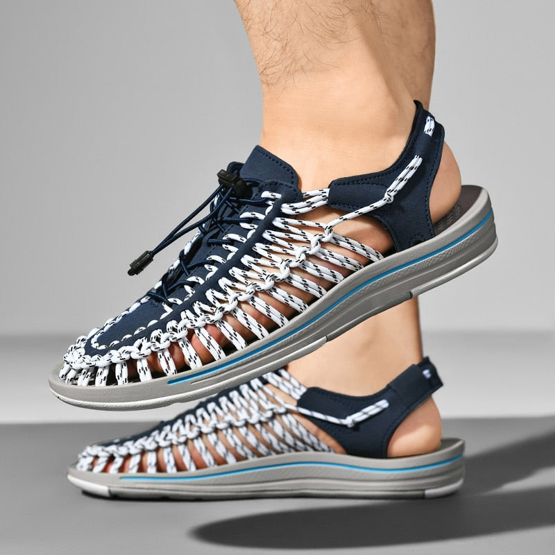 Navy and white sandals worn by a person on a gray background