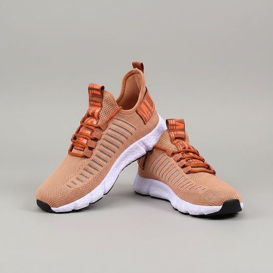 Brown and orange sneakers with white soles on a wooden floor.