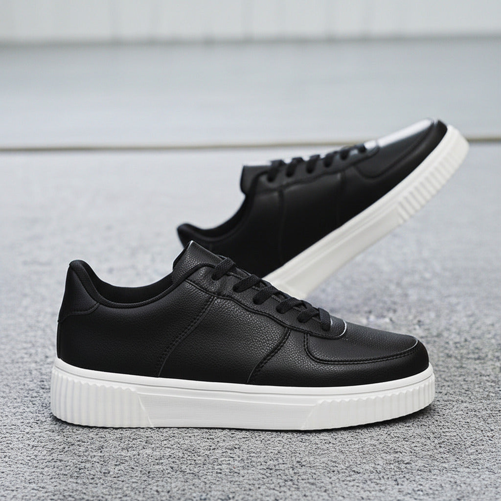 Black sneakers with white soles worn by a person, with an IKEA basket in the background.