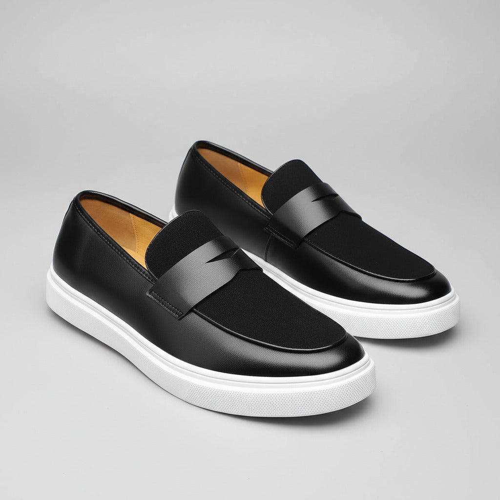 Black loafers with white soles on a wooden surface