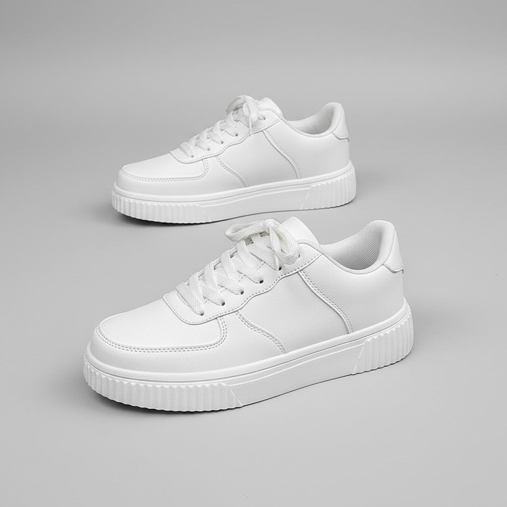 White sneakers on a person's feet with a gray background