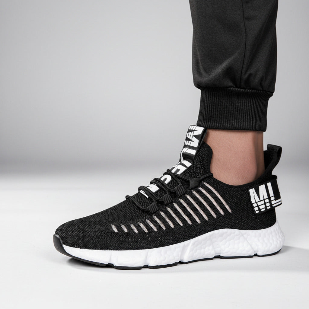 Black and white athletic shoes worn by a person on a wooden floor.