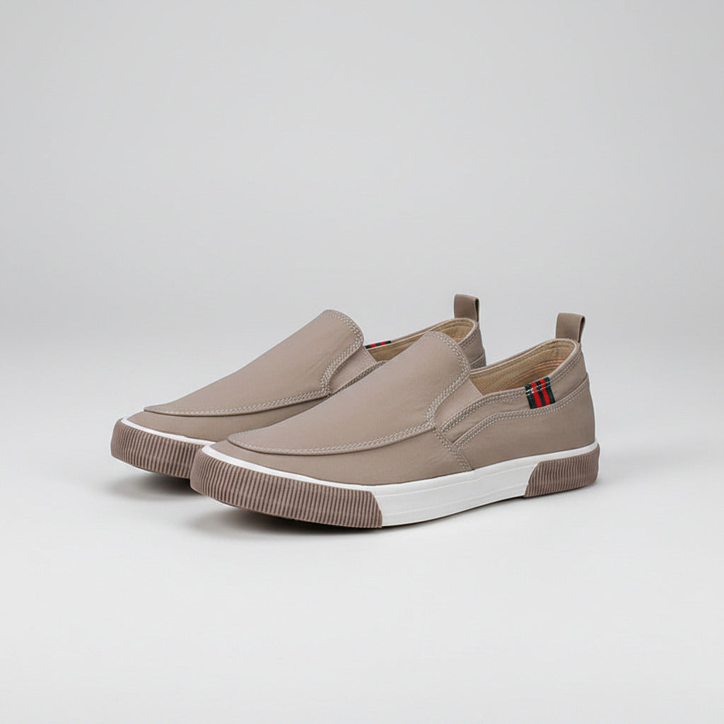 Beige slip-on shoes with a small flag detail on a white background