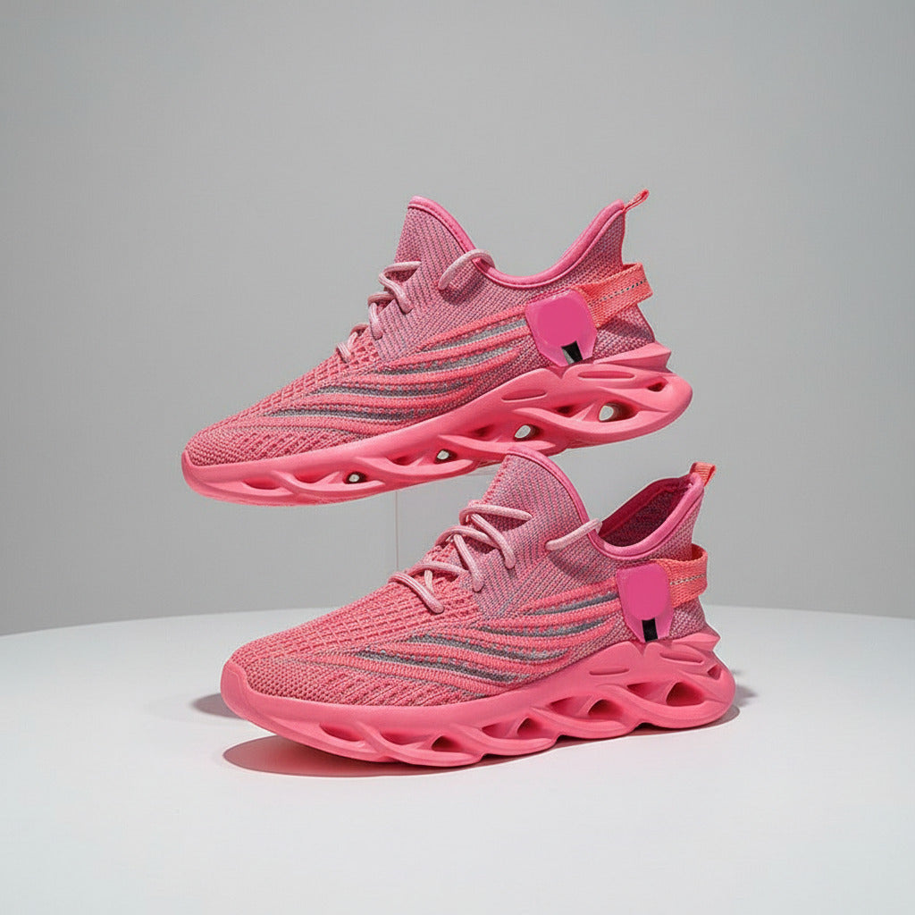 Pink athletic shoes with a textured design held by a person against a blue background