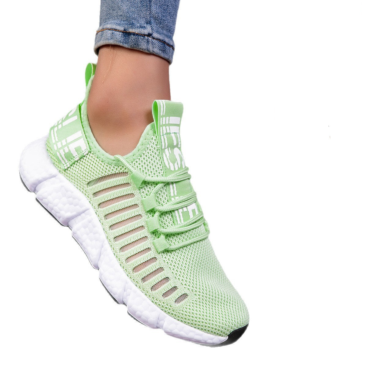 Green running shoes with white soles worn by a person on a white background