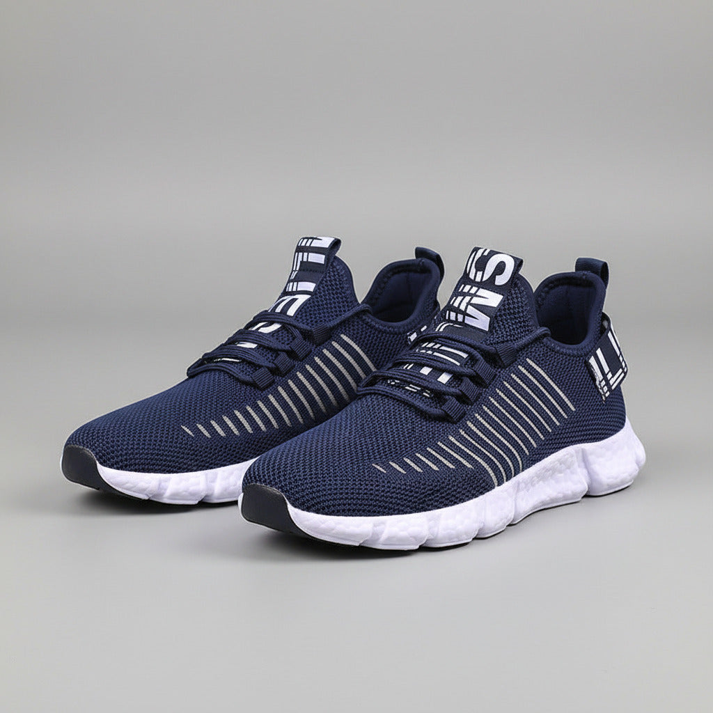 Navy blue athletic shoes with white soles worn by a person on a wooden floor.