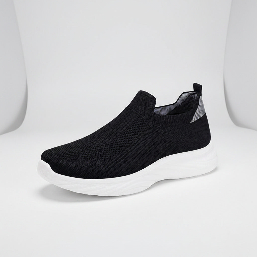 Black slip-on sneaker with white sole on a white background