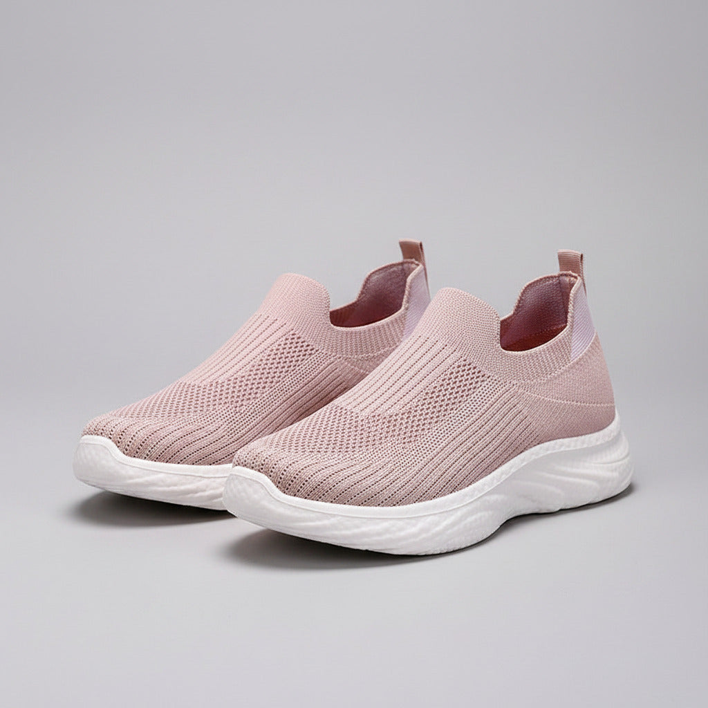 Pink slip-on sneakers with white soles on a wooden floor.