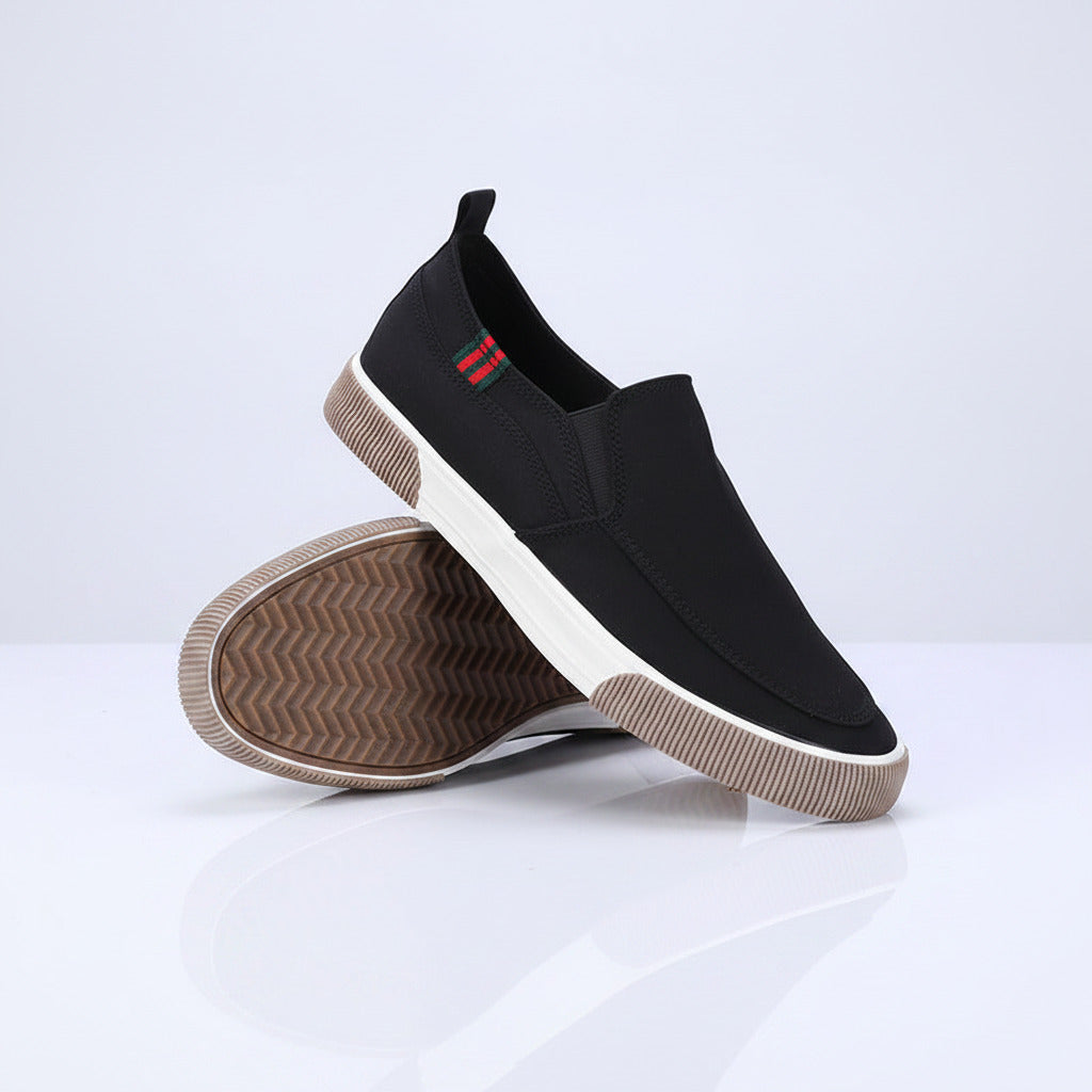 Black slip-on shoes with white soles on a gray background