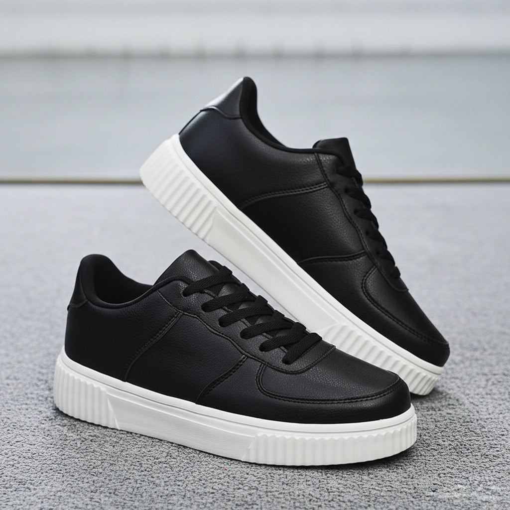 Black sneakers with white soles worn by a person, with an IKEA basket in the background.
