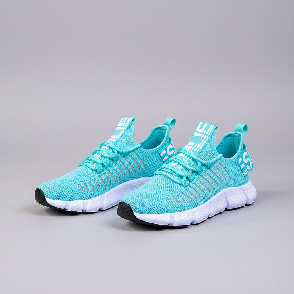 Teal running shoes with white soles worn by a person on a wooden floor.