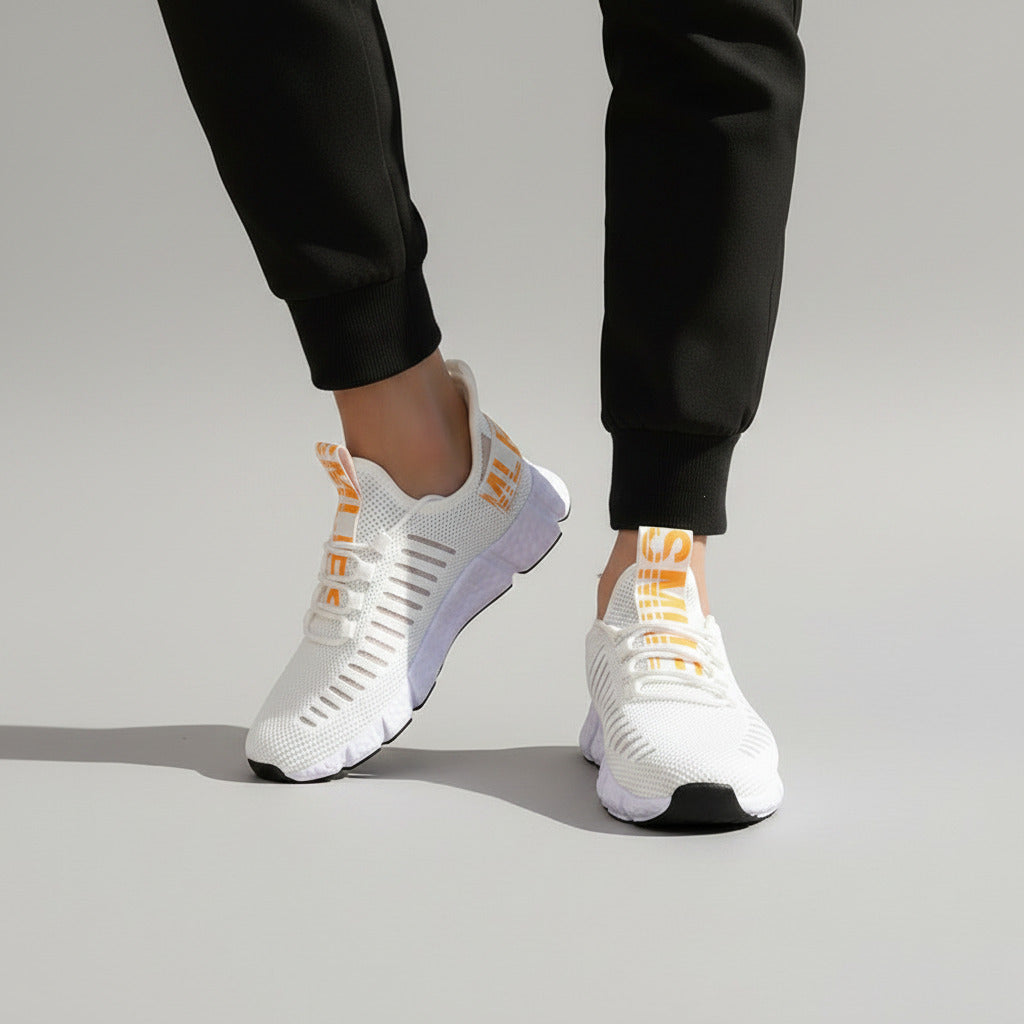 White sneakers with orange accents worn indoors on a wooden floor.